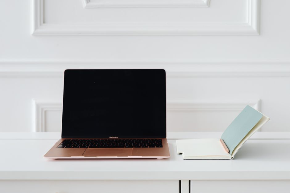 A clean, minimalist desk setup with a gold laptop and open notebook, perfect for productivity.