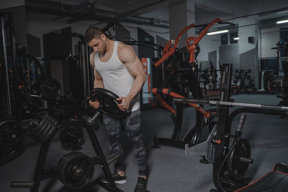 Muscular man lifting weights in a well-equipped gym for strength training.